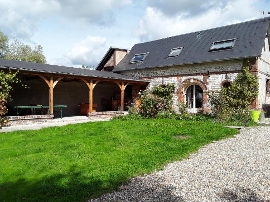 a brick house with a porch and a green yard at La Petite Maison arc-en-ciel in La Feuillie