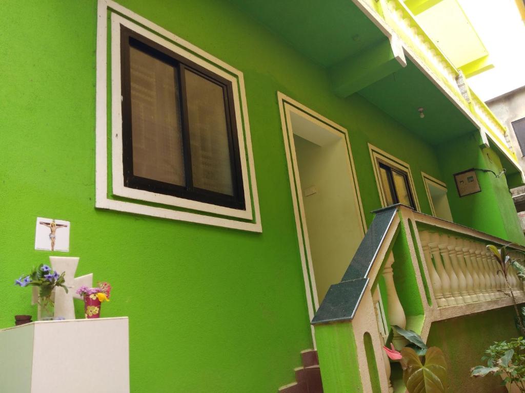 una casa verde con una escalera y una pared verde en Luiza Guest House en Baga