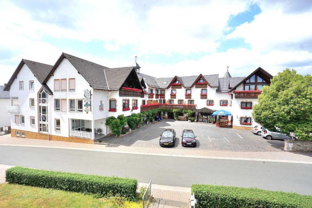 un gran edificio con coches estacionados en un estacionamiento en Hotel - Restaurant BERGHOF en Berghausen