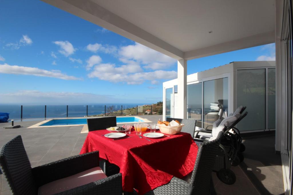 a dining room with a red table and a view of the ocean at Villa Por do Sol in Estreito da Calheta