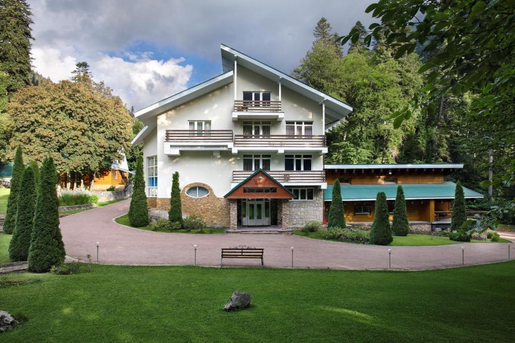 a large white house with a bench in a yard at Hotel Belalakaya in Dombay