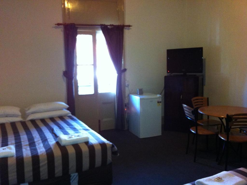 a room with a bed and a table and a window at Hotel Metropolitan in Adelaide