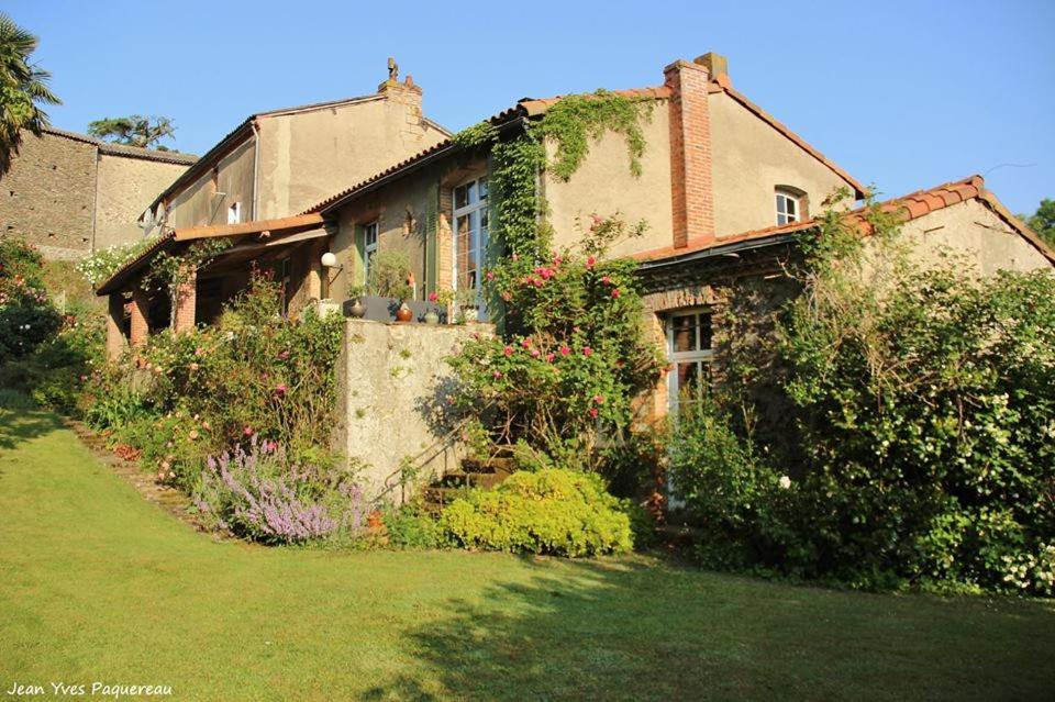 una casa vieja con plantas y flores en el patio en Le Moulin Neuf en Beaupréau