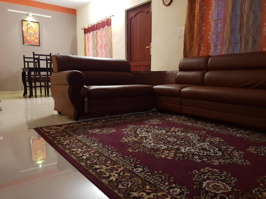 a living room with a brown couch and a rug at SP Plaza Service Apartment in Trivandrum
