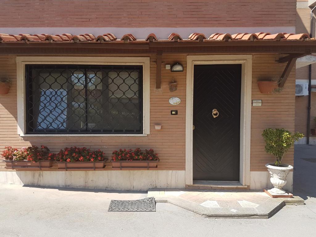 a house with a black door and flowers in a window at Bed & Breakfast "A Casa di Anto" in Mentana