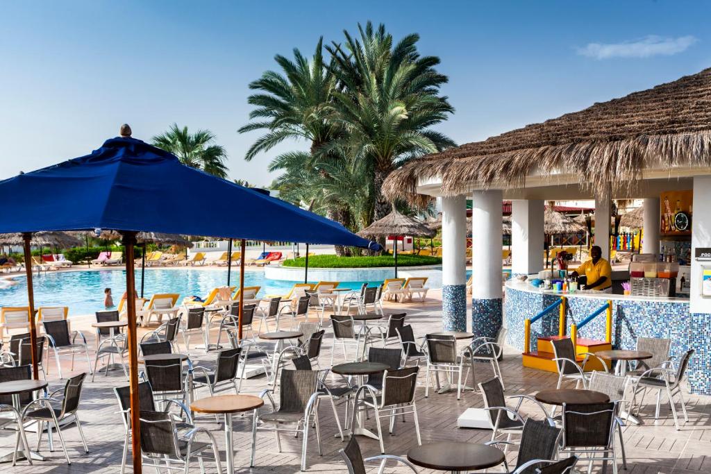 a pool with chairs and tables and a blue umbrella at TUI MAGIC LIFE Penelope Beach - Families & Couples in Midoun