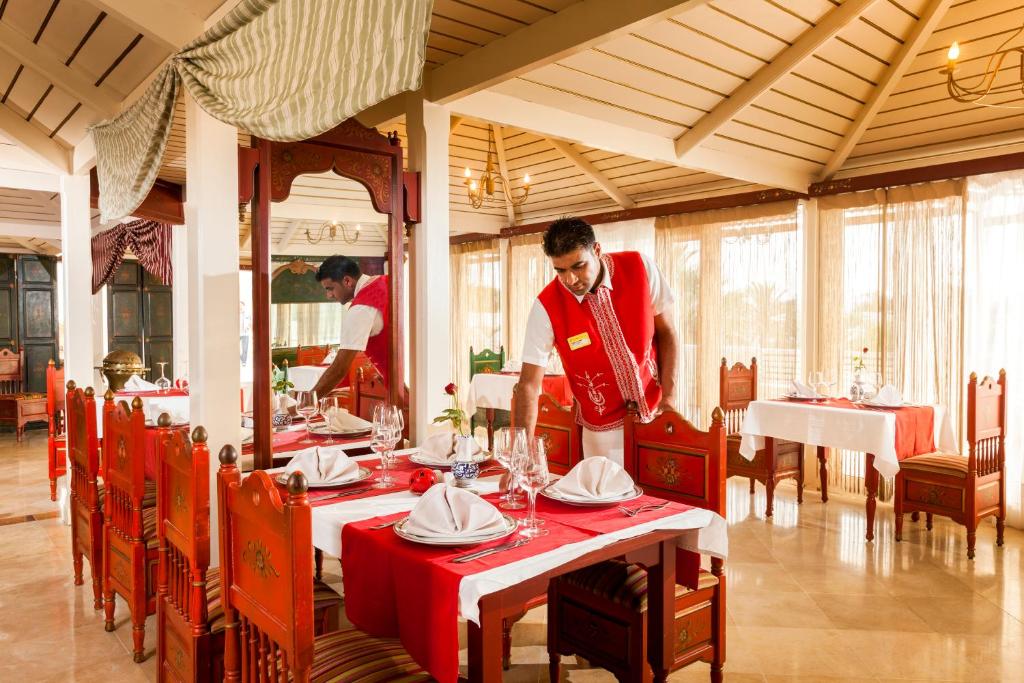 a man is setting a table in a restaurant at TUI MAGIC LIFE Penelope Beach - Families & Couples in Midoun