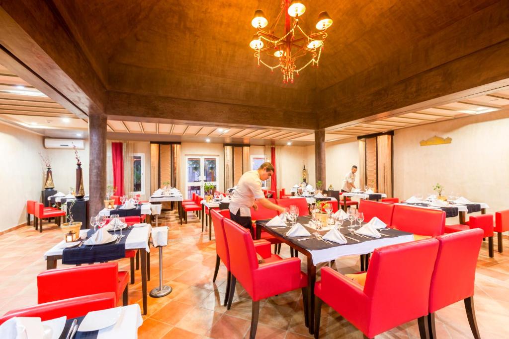 a man standing in a dining room with tables and red chairs at TUI MAGIC LIFE Penelope Beach - Families & Couples in Midoun