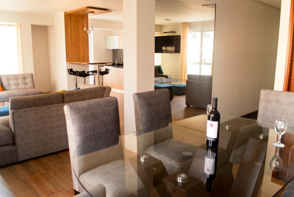 una sala de estar con una mesa con una botella de vino. en Residencial Cafferata, en Lima