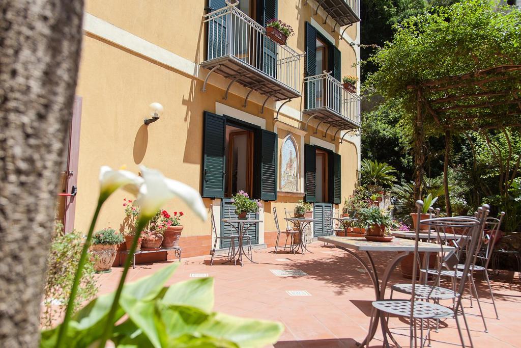 an outdoor patio with tables and chairs and a building at Hotel L'Argine Fiorito in Atrani