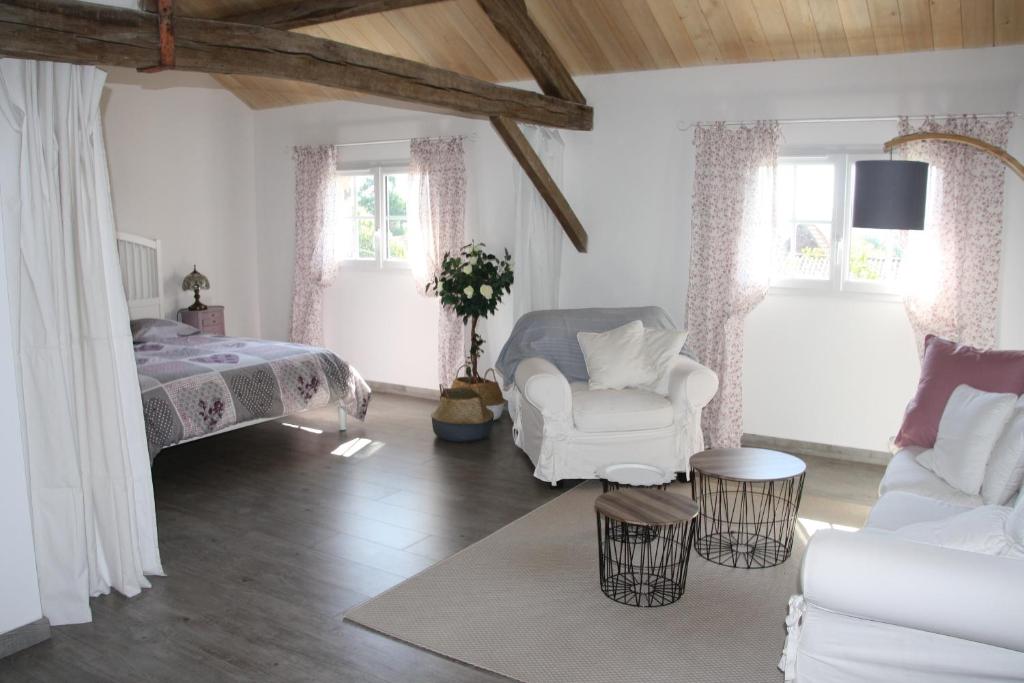 a white bedroom with a bed and a white chair at le petit durbec in La Force