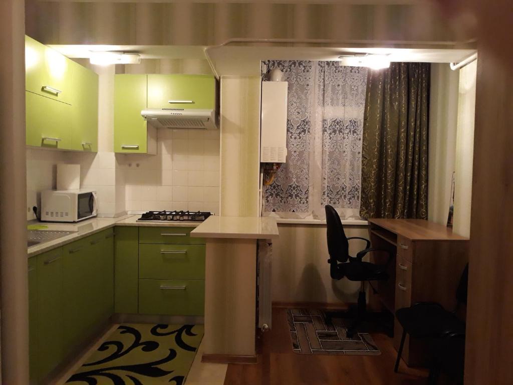 eine kleine Küche mit grünen Schränken und einer Mikrowelle in der Unterkunft Geo Apartament in Iaşi