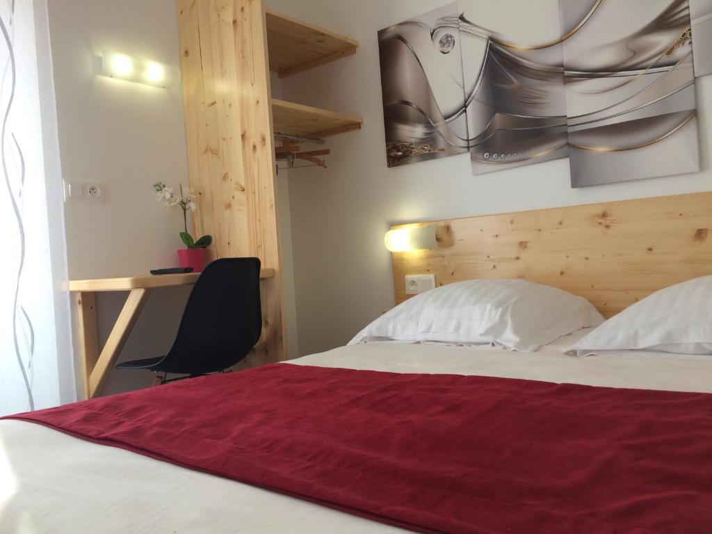 a bedroom with a bed with a red blanket on it at hotel le beauséjour in Langogne