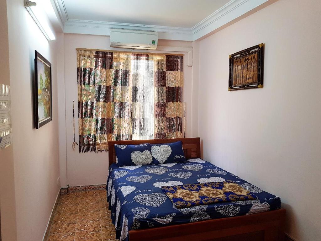 1 dormitorio con 1 cama con edredón azul y ventana en Hanu's House, en Hanói