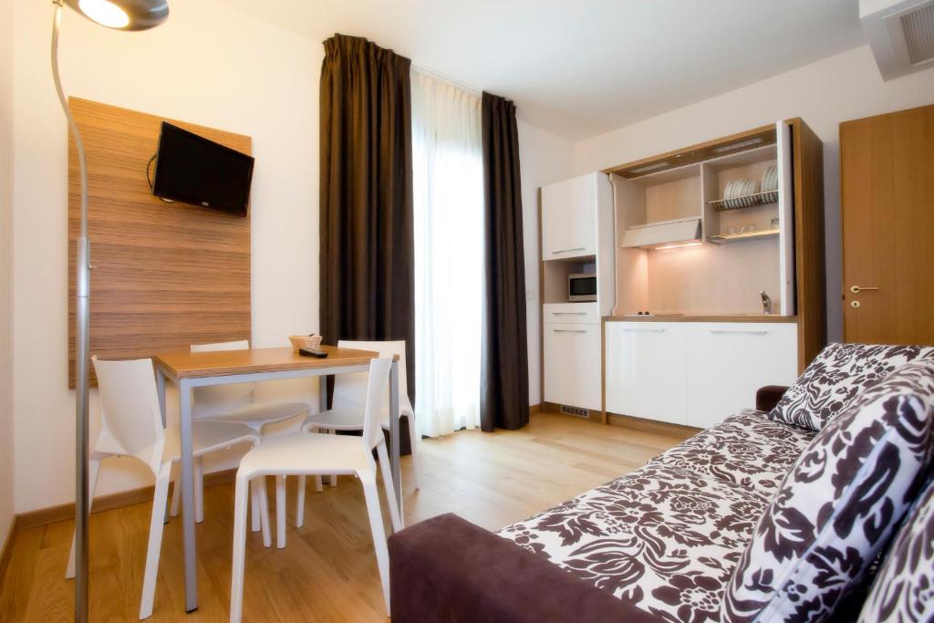 a living room with a bed and a table with a dining room at Hotel Marco Polo in Lido di Jesolo