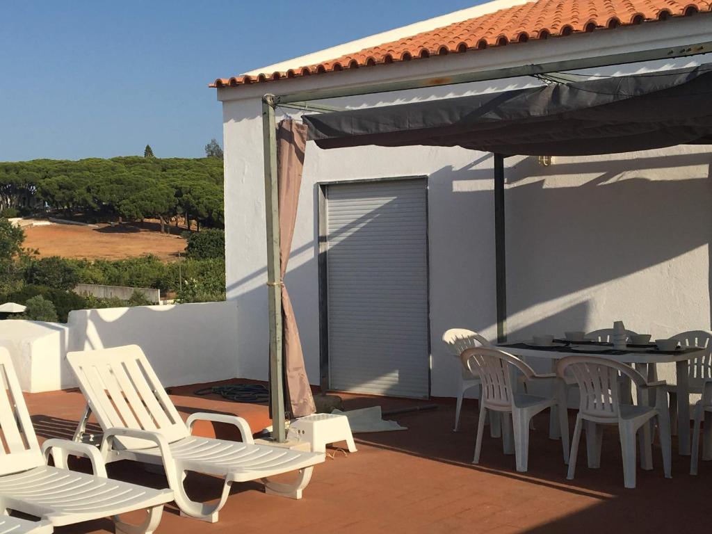 een patio met witte stoelen en een tafel op een terras bij Casa Caminhos in Porches