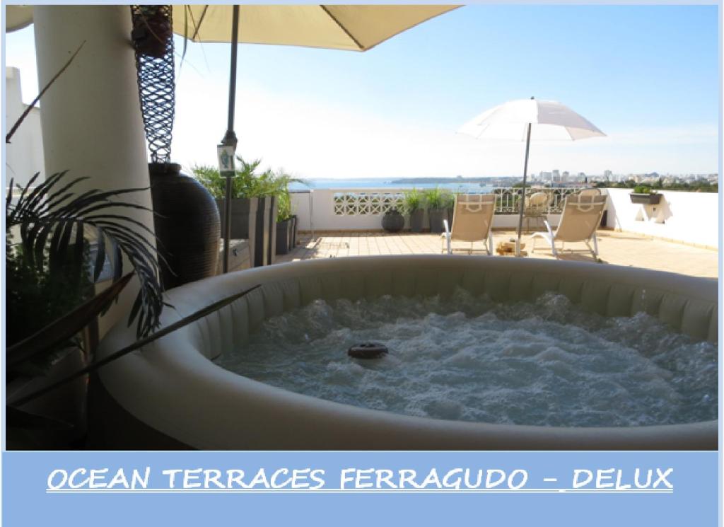uma banheira de hidromassagem num pátio com um guarda-sol em Ocean Terraces Vila Gaivota I em Ferragudo
