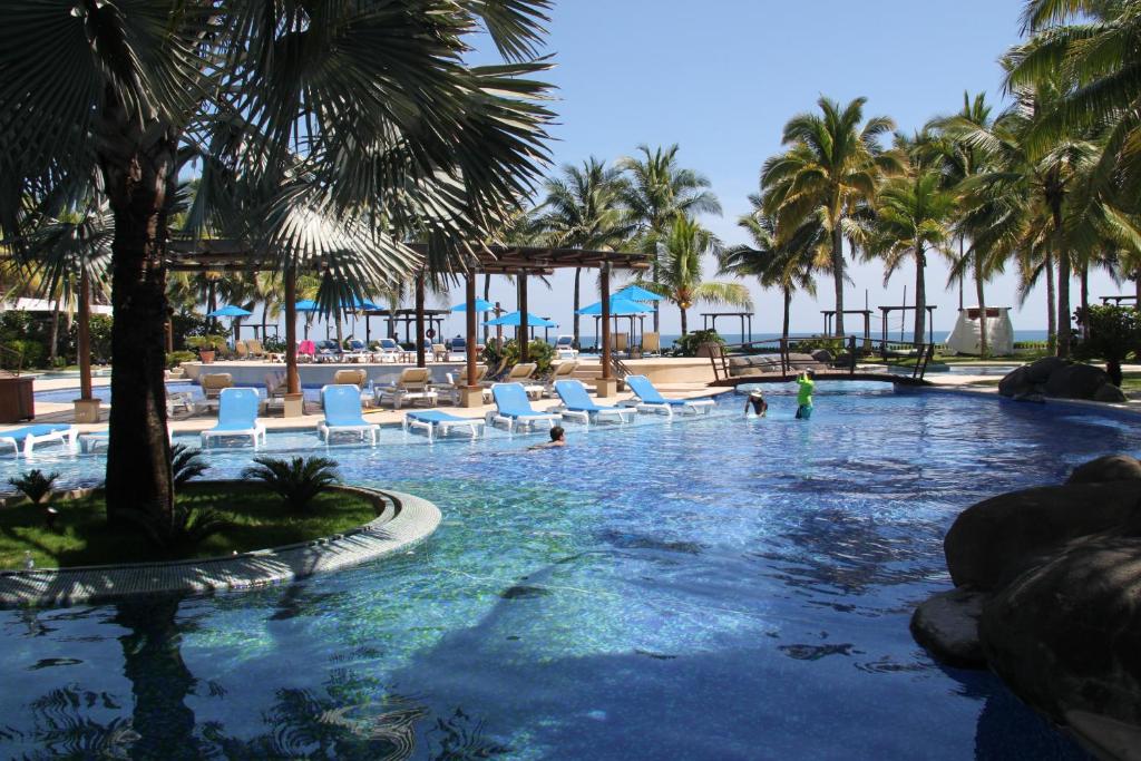 una piscina en un complejo con sillas y palmeras en Villa 24C Los Cabos Monterrico, en Monterrico
