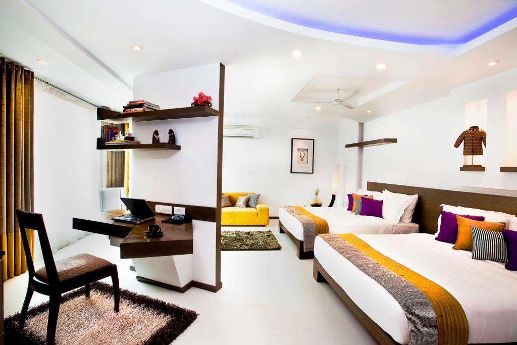 a hotel room with two beds and a desk at Melange Astris in Bangalore