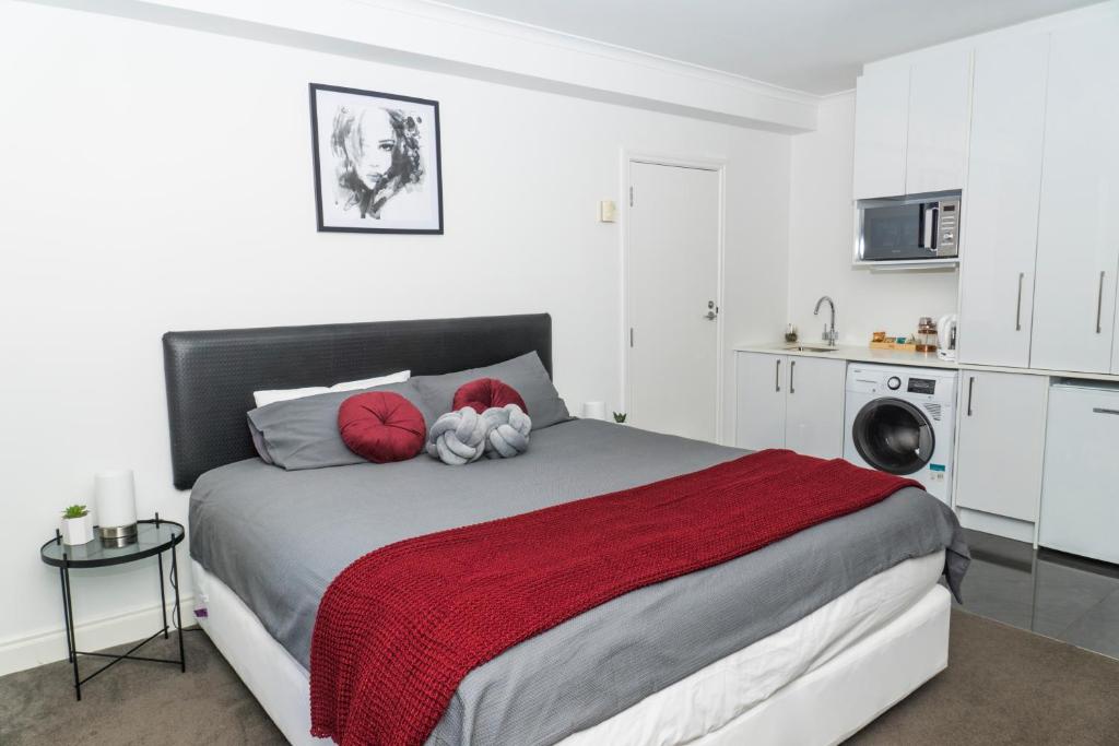 a bedroom with a large bed with red pillows at Auckland Centre Studio w/ Pool and Gym in Auckland