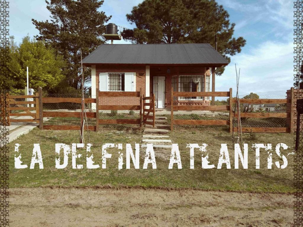 una pequeña casa con una valla y un cartel que lee la detina a los elementos en La Delfina Atlantis en Mar de Ajó