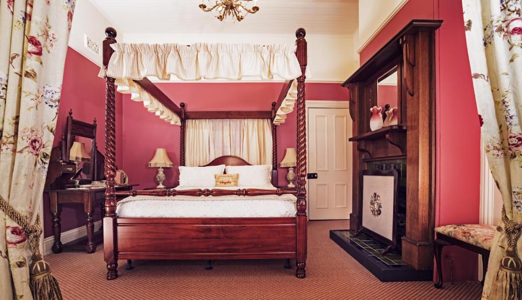 a bedroom with a canopy bed and a fireplace at Kurrara Historic Guest House in Katoomba