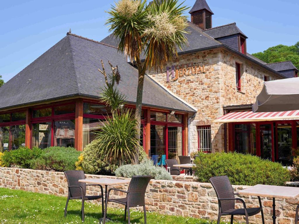 a patio with tables and chairs in front of a building at Mercure Dinan Port Le Jerzual in Dinan