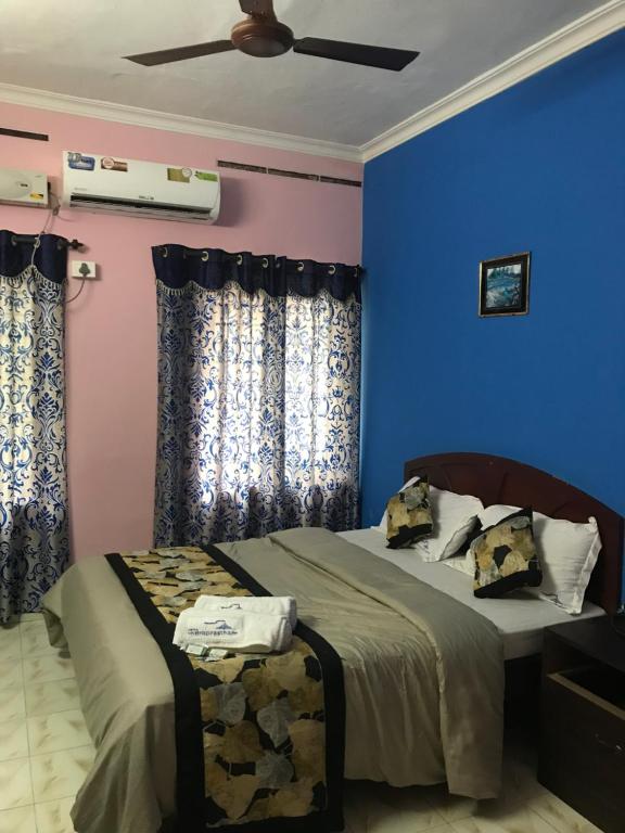 a bedroom with blue and pink walls and a bed at Indraprastham Tourist Home in Kottayam