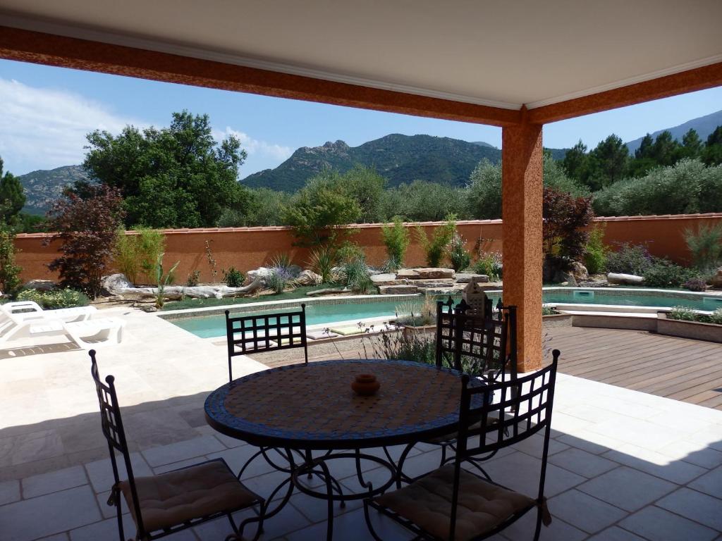un patio con mesa, sillas y piscina en Villa SOREDE, en Sorède
