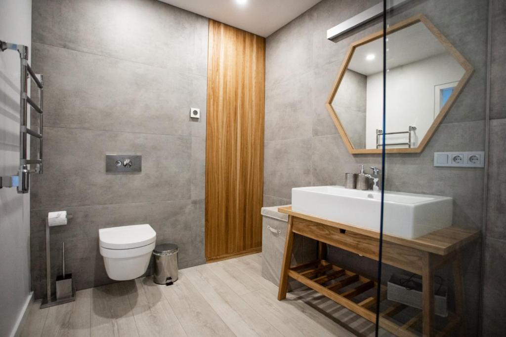 a bathroom with a sink and a toilet and a mirror at G - Owl Jazz - Modern and spacious loft type apartment 8 with free private parking in Kaunas
