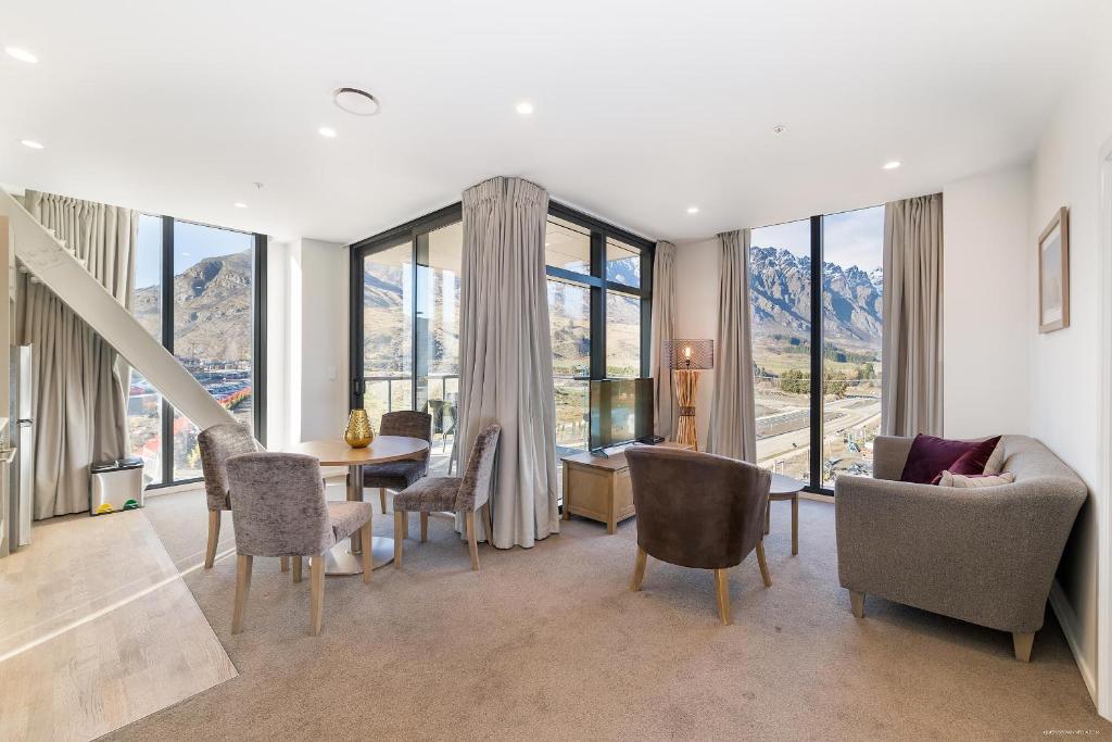 a living room with a table and chairs and windows at Executive 2 Bedroom Apartment Remarkables Park in Queenstown