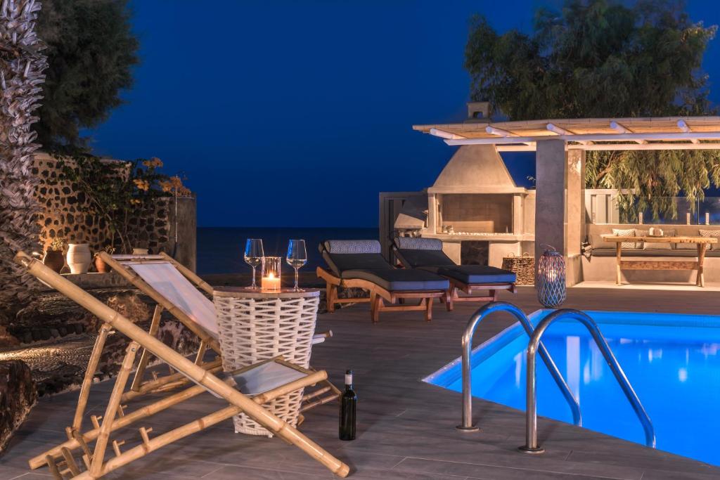 a villa with a swimming pool at night at Damma Beachfront Luxury Villa in Kamari