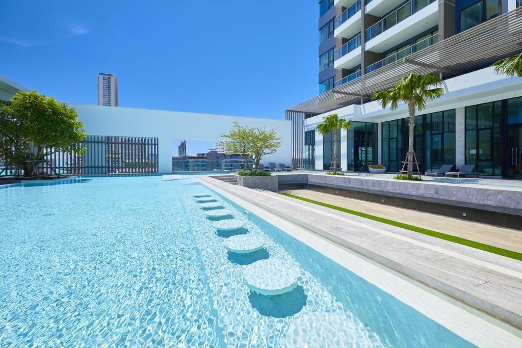 a swimming pool in front of a building at Kuno - 2Br, Beachfront Jomtien in Jomtien Beach