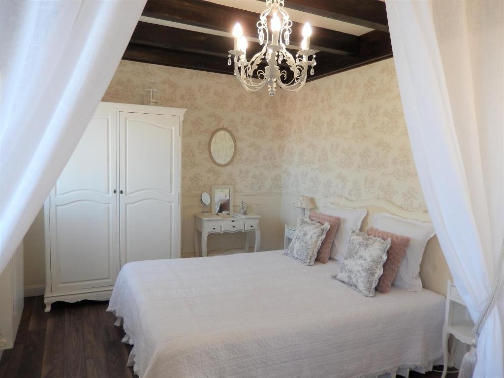 sypialnia z białym łóżkiem i żyrandolem w obiekcie La Cordonnerie de Réau w mieście Réau