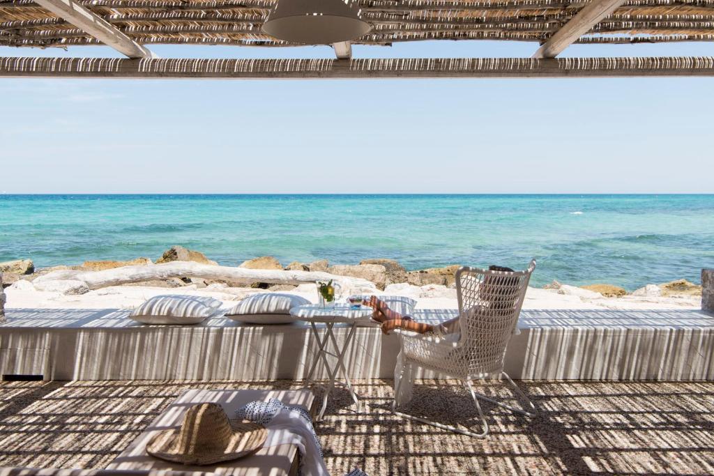 une personne assise sur une chaise sur la plage dans l'établissement La Peschiera, à Savelletri di Fasano