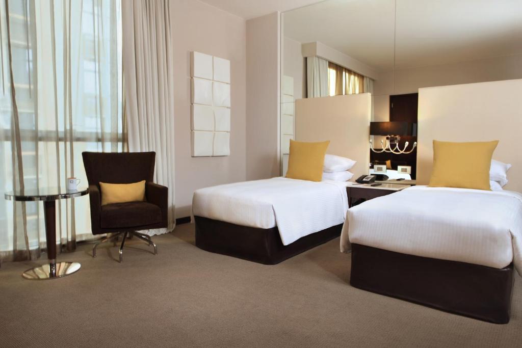 a hotel room with two beds and a chair at Centro Al Manhal by Rotana in Abu Dhabi