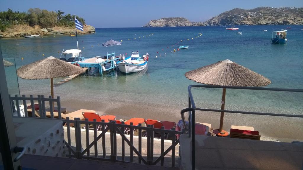 a beach with chairs and boats in the water at Komissa΄s Beach House in Agia Pelagia