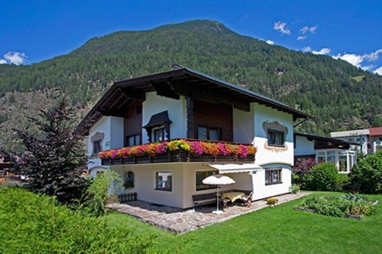 ein Haus mit einem Balkon mit Blumen darauf in der Unterkunft Ferienwohnungen Plattner in Längenfeld