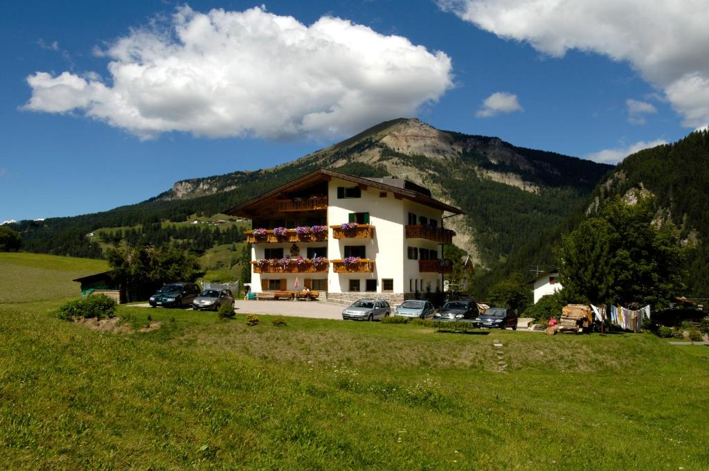 a building with cars parked in front of a mountain at Villa Insam Apartment in Selva di Val Gardena