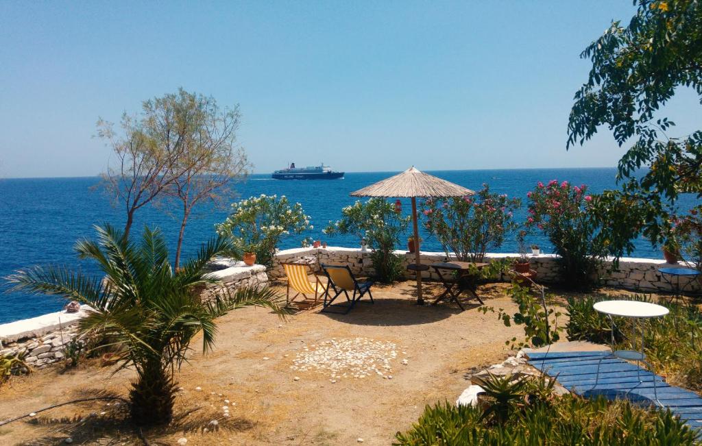 eine Terrasse mit einem Tisch, einem Sonnenschirm und dem Meer in der Unterkunft Agriolykos Pension in Agios Kirykos