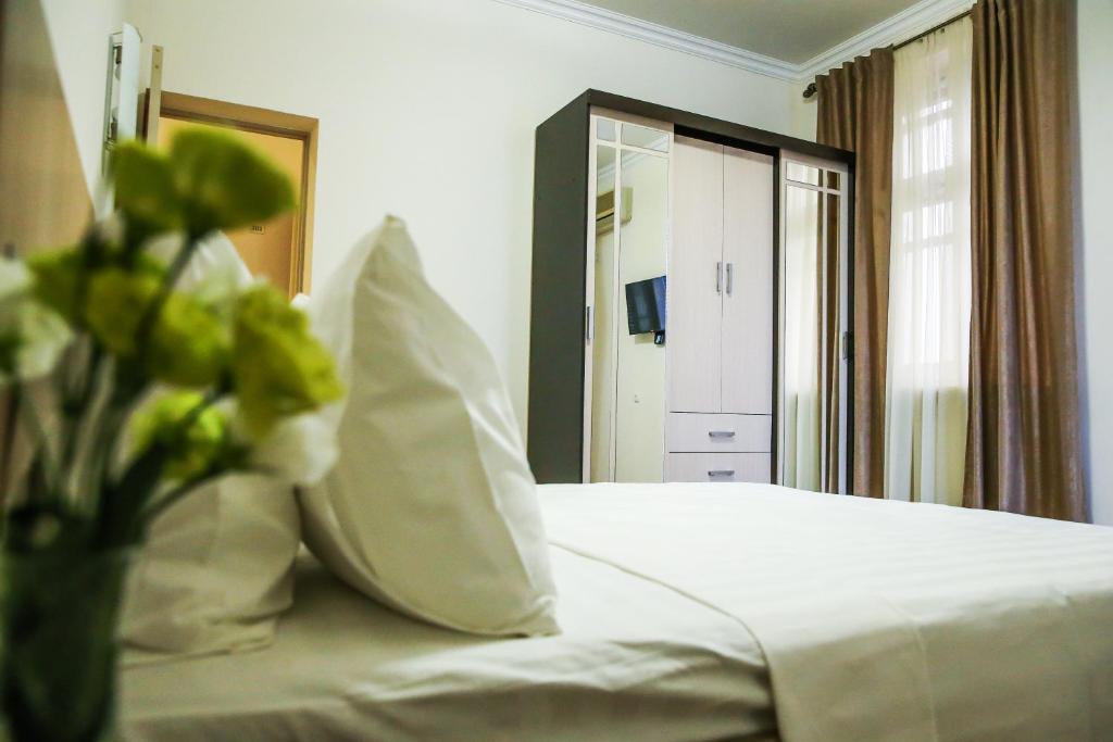 a bedroom with a white bed with a vase of flowers at Alba Hotel Yerevan in Yerevan