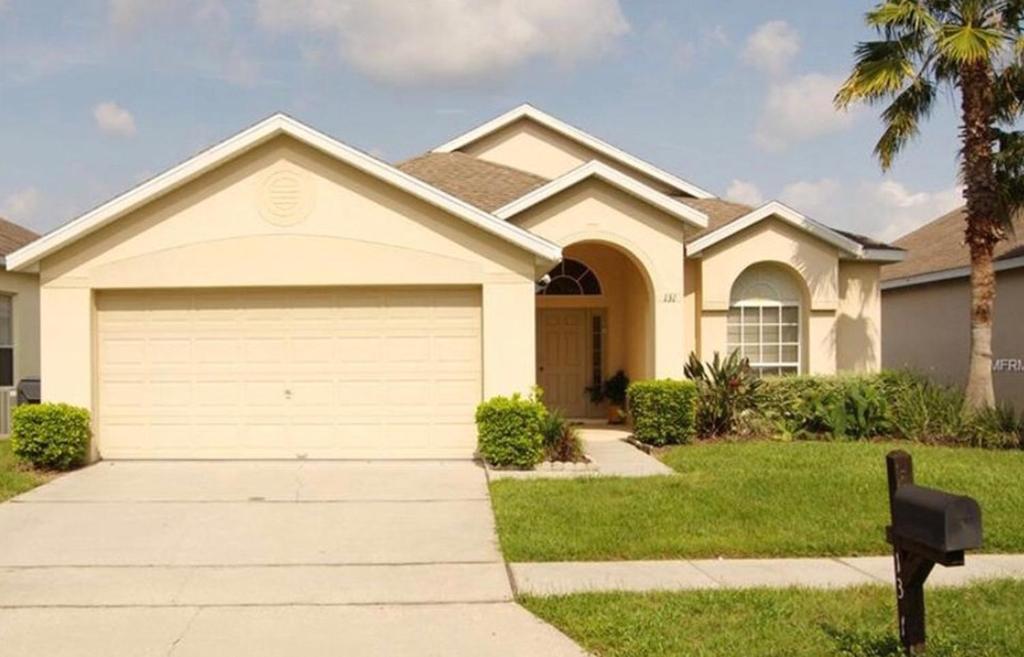 a house with a garage and a palm tree at Pool Home 15 Minutes From Disney in Davenport