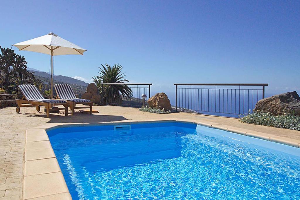 a swimming pool with a bench and an umbrella at Casa Ceferino in Tijarafe