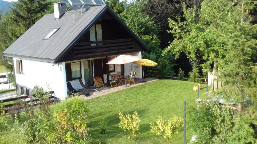 a small white house with a lawn and an umbrella at Holiday House Bohinj in Bohinj