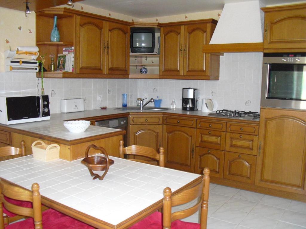 a kitchen with wooden cabinets and a table in it at Vacances à Réthoville in Réthôville