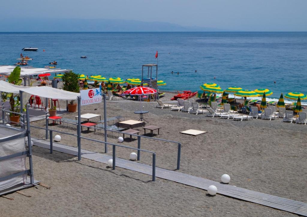 - une plage avec des chaises longues, des parasols et l'eau dans l'établissement Casa Nonna Elvira, à Roccalumera