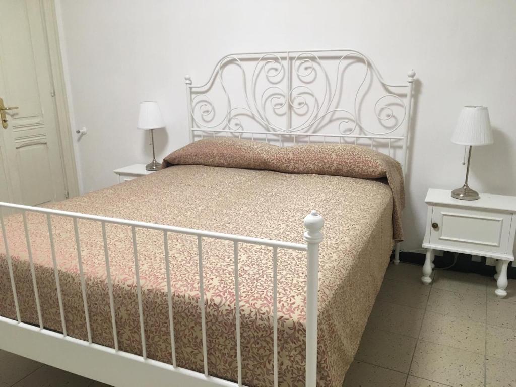 a white bed in a bedroom with two night stands at B&B Juighissa Leonora in Oristano