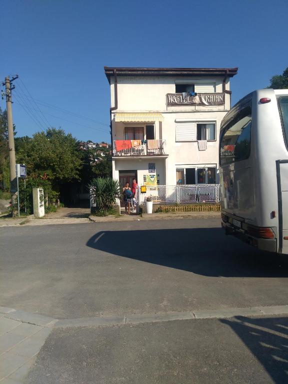 a white bus parked in front of a building at Hostel Trajan in Donji Milanovac