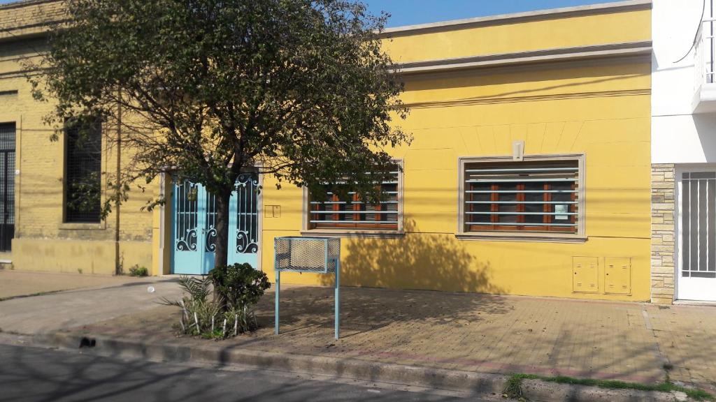 un edificio amarillo con un árbol delante de él en La Glicina casa en La Plata