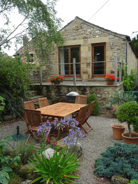 a wooden table and chairs in front of a house at The Barn in Bedale